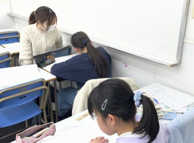 宿題を一生懸命に頑張る生徒と分からないところを教える先生です。
