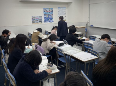 宿題やテキストを一生懸命に頑張る生徒と分からないところを教える先生です。